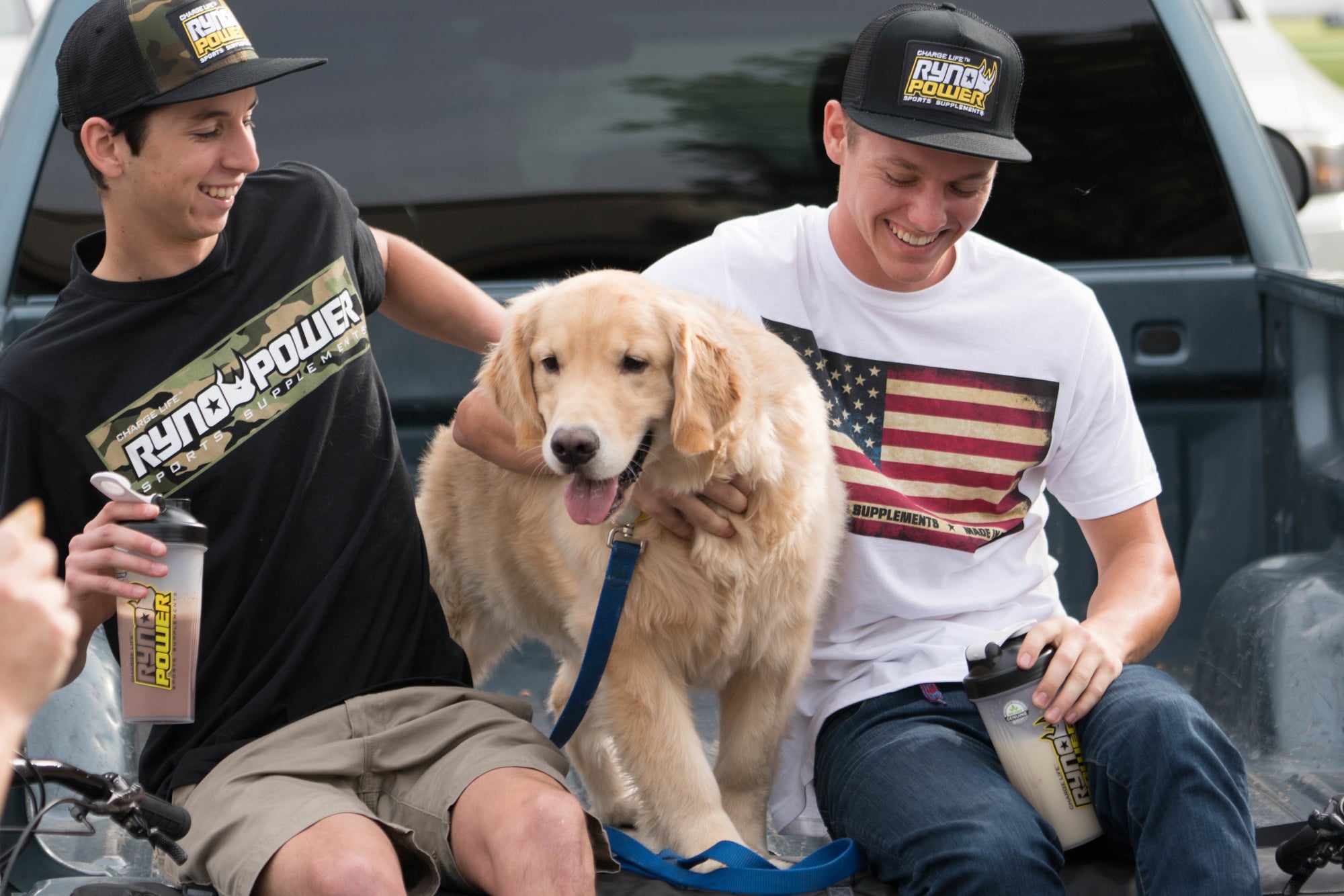 people casually sitting with dog holding protein shaker bottles